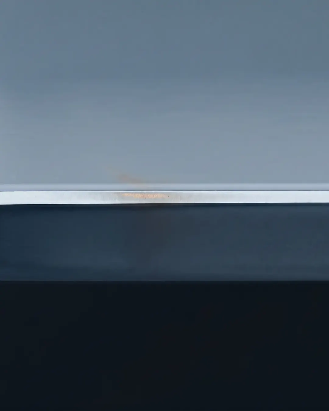 Macro cross-section of a thin bright coating layer over a dark steel substrate
