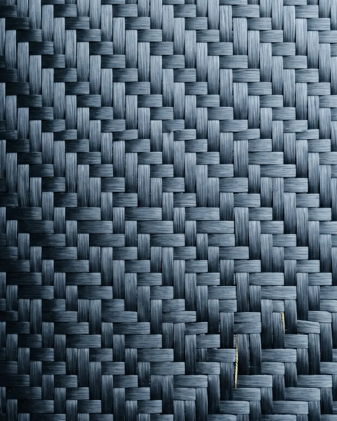 Macro of a woven carbon-fibre twill in cold monochrome