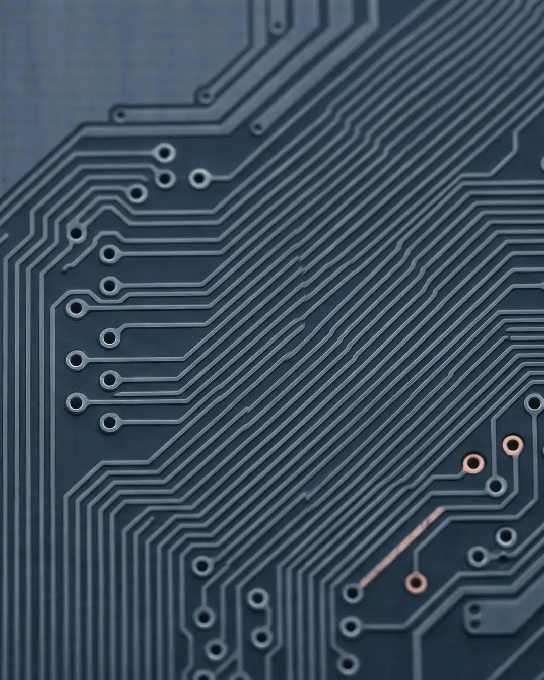 Macro of fine conductive traces on a dark electronic substrate in cold monochrome