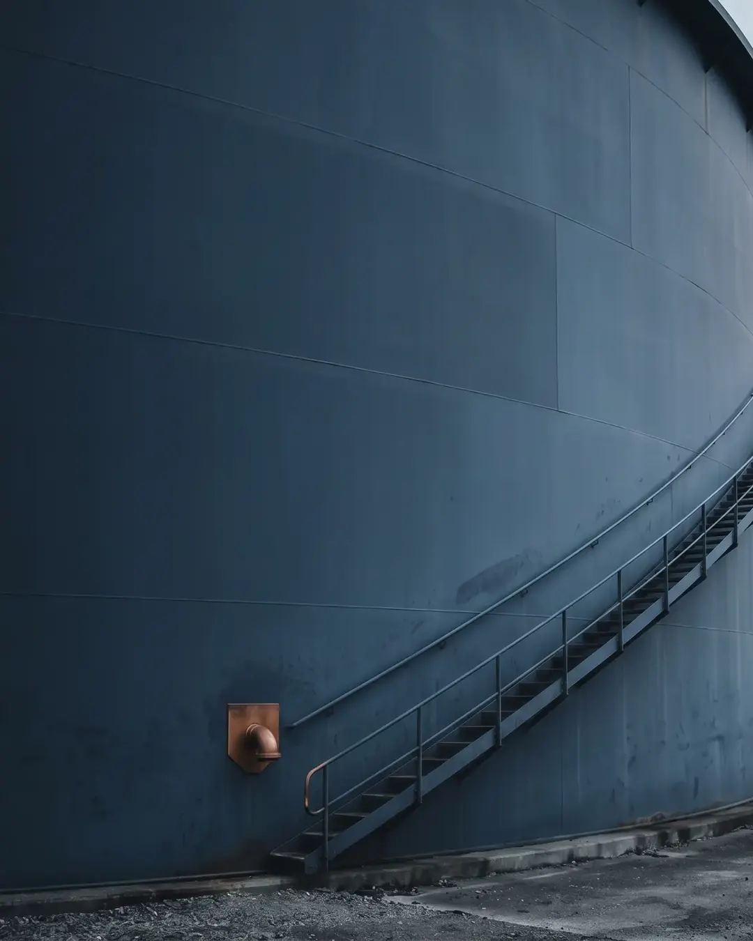 The curved wall of an above-ground tank crossed by a faint magnetic-track path